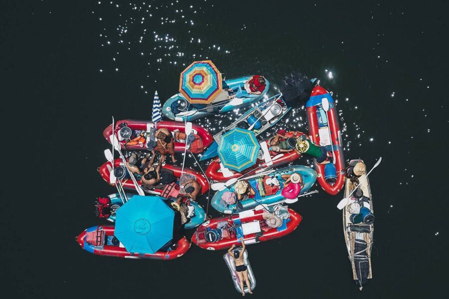An aerial view of a group of rafts floating on a large river. contact us.